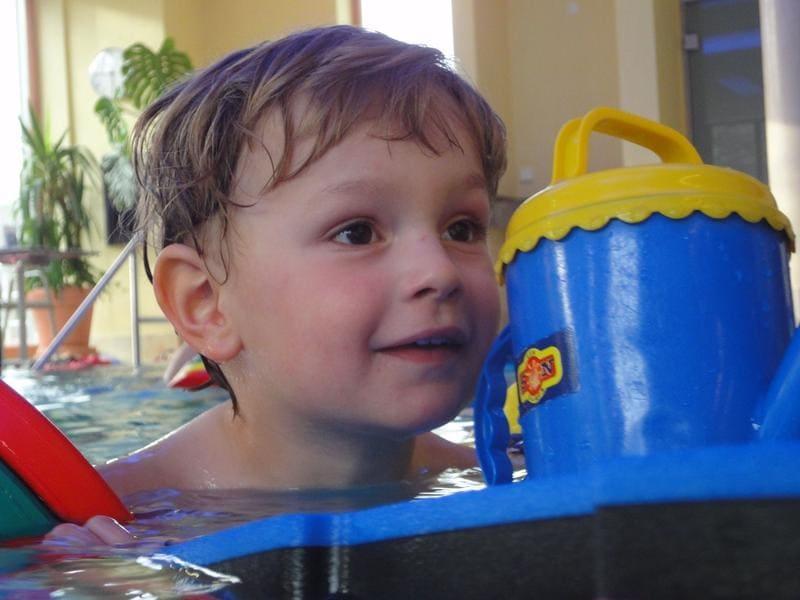 Kind spielt mit Eimer im warmen Wasser