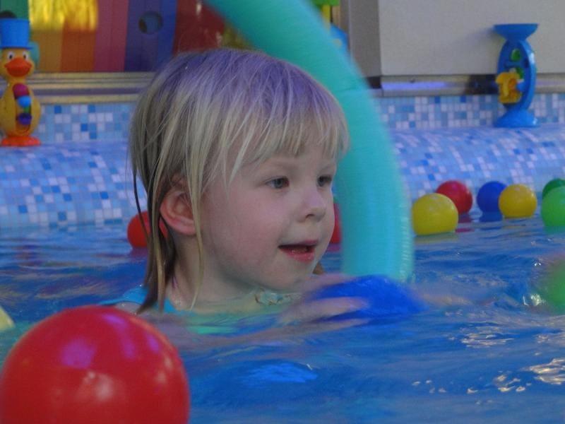 Kind spielt mit bunten Bällen im Wasser